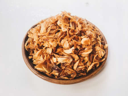 Pile of Onion fries or shallots with spread in several sides on wood plate isolated on white background.の写真素材