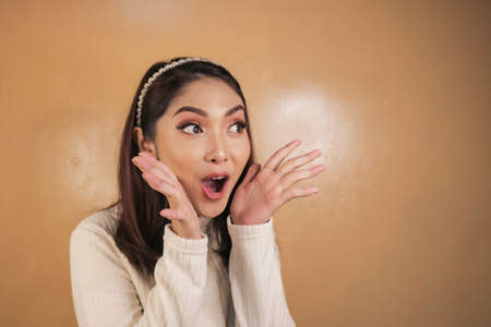 Wow and shocked face of Young Asian woman with open hand gesture. Advertising model concept.の写真素材
