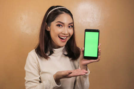 Happy and smiling young Asian women showing a green blank screen.