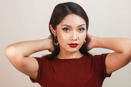 A fierce-looking Asian woman in a red shirt posing in front of white background