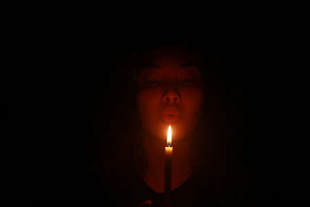 Asian woman blowing candle in the dark nightの写真素材