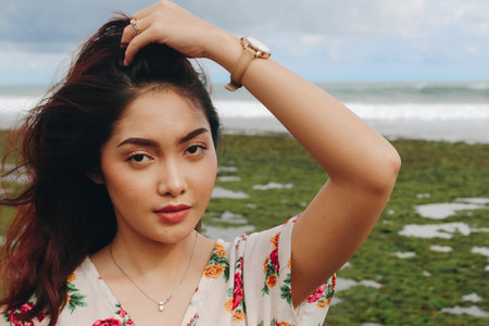 A young beautiful Asian woman flipping her hair at the beach