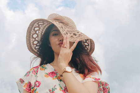 A young cute Asian girl wearing a sun hat is relaxing on the blue sky beach at Gunungkidul, Indonesiaの写真素材