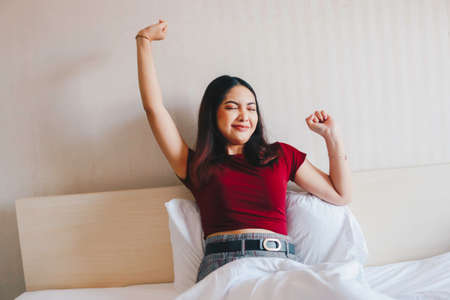 A portrait of sleepy young Asian woman yawning on bedの写真素材