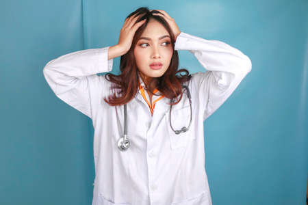 A portrait of a young Asian female doctor looks tired and overworked