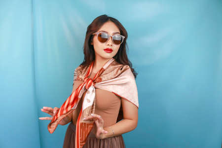 Young Asian confident woman is posing isolated by a blue background.の写真素材