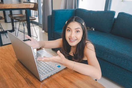 A young Asian woman is smiling while sitting on the couch in the living room.