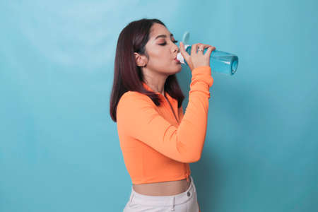 Asian young woman drinking a bottle of water after workout exercising.