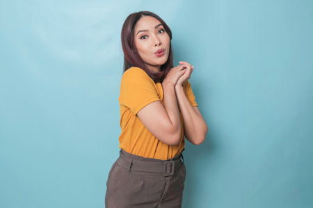 Surprised Asian woman reclines on her hands and looking at the camera over blue backgroundのeditorial素材