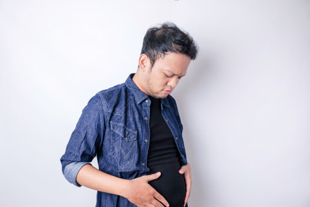 A portrait of insecure Asian fat man is holding the fat around his waistの写真素材