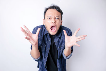 A dissatisfied young Asian man looks disgruntled wearing blue navy shirt irritated face expressionsの写真素材
