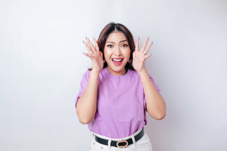 A portrait of a shocked Asian woman wearing a lilac purple t-shirt, isolated by a white backgroundの写真素材