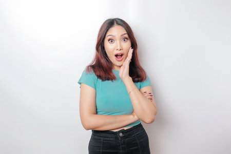 A portrait of a shocked Asian woman wearing a blue t-shirt, isolated by a white backgroundの写真素材