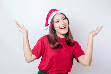 Happy Asian Santa woman is smiling and pointing up on top of her isolated by a white background....