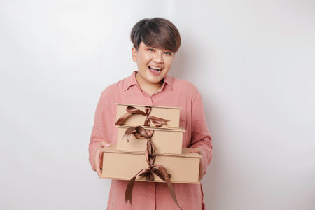A happy young woman is wearing pink shirt and holding presents or shopping bag.の写真素材