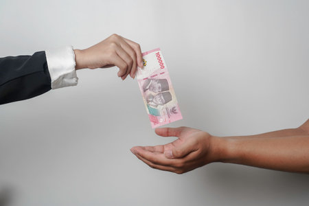 A portrait of businessman giving money in Indonesian Rupiah for business deal or payment or charity