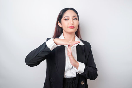 Hispanic Asian businesswoman wearing black suit doing time out gesture with hands, frustrated and serious faceの写真素材