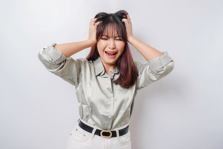 A portrait of an Asian woman wearing a sage green shirt isolated by white background looks depressedの写真素材