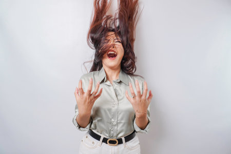 A young Asian woman with a happy successful expression wearing sage green shirt isolated by white backgroundの写真素材