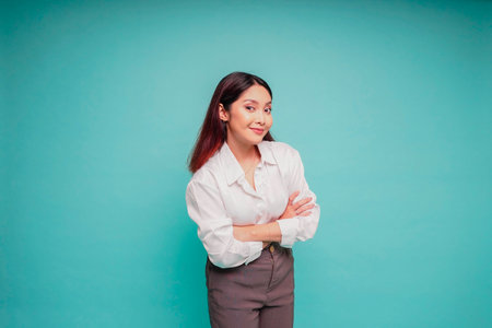 Portrait of a confident smiling Asian woman wearing white shirt standing with arms folded and...