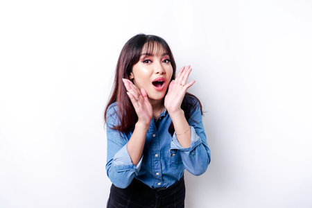 Young beautiful woman wearing a blue shirt shouting and screaming loud with a hand on her mouth. communication concept.の写真素材