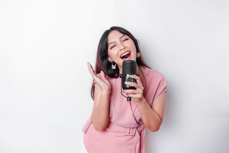Portrait of carefree Asian woman, having fun karaoke, singing in microphone while standing over...