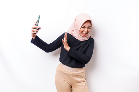 Young Asian Muslim woman isolated on white background, looks depressed, face covered by arms...