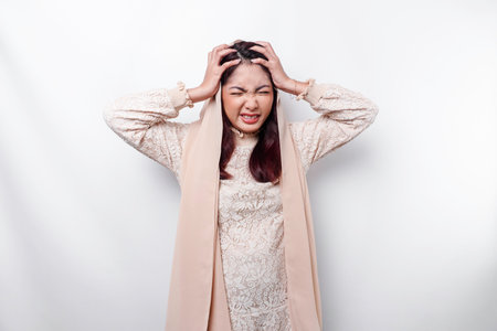 A portrait of an Asian Muslim woman wearing a headscarf isolated by white background looks depressedの写真素材