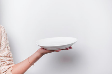 Close-up, holding a white plate and spoon, isolated on a white background.の写真素材