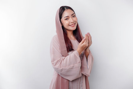 Religious beautiful Asian Muslim girl wearing a headscarf praying to God, isolated by white backgroundの写真素材