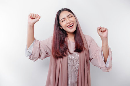 A young Asian Muslim woman with a happy successful expression wearing a hijab isolated by white backgroundの写真素材