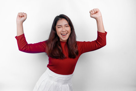 A young Asian woman with a happy successful expression wearing red top isolated by white backgroundの写真素材
