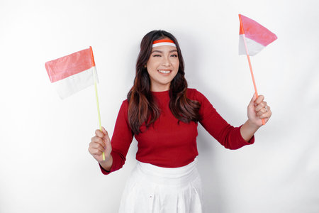 Excited young Asian woman celebrate Indonesian independence day holding the Indonesian flag isolated on white backgroundの写真素材