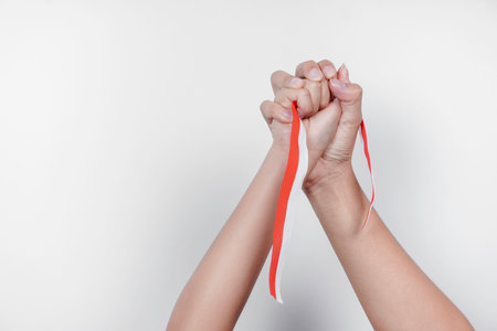 hands put together holding Indonesian red and white ribbon. Indonesia's independence day conceptの写真素材