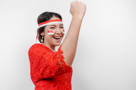 A young Asian woman with a happy successful expression wearing red kebaya and headband isolated by white background. Indonesia's independence day concept.の写真素材