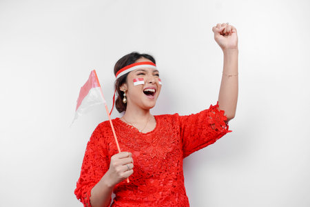 A young Asian woman with a happy successful expression wearing red kebaya and headband isolated by white background. Indonesia's independence day concept.の写真素材