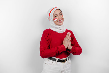 A friendly Indonesian muslim woman is wearing red top and white hijab gesturing traditional greeting...