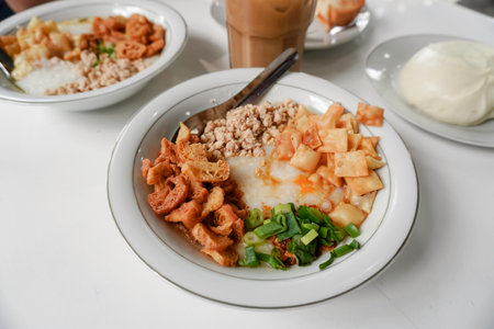 Bubur ayam or Chicken Porridge, Indonesian traditional food consist of white rice porridge, shredded chicken, cakwe, crackers, and leek. Selective focus.の写真素材