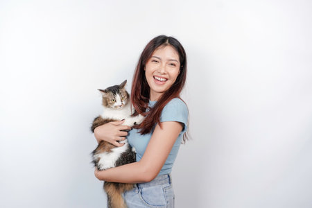 Portrait of young Asian woman holding cute angora cat with yellow eyes. Female hugging her cute long hair kitty isolated by white background. Adorable domestic pet concept.の写真素材
