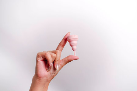 Close up of woman hand holding menstrual cup over white background. Women health concept, zero waste alternativesの写真素材