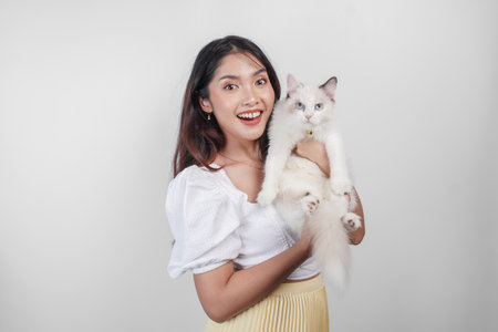 Portrait of young Asian woman holding cute ragdoll cat with blue eyes. Female hugging her cute long hair kitty isolated by white background. Adorable domestic pet concept.の写真素材