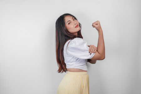 A portrait of Asian woman showing strong gesture by lifting her arms and muscles smiling proudly.の写真素材