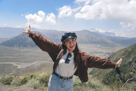 An Asian girl standing on a hill track in Bromo, enjoying view of Bromo, a wonderful scenery in dramatic hillの写真素材