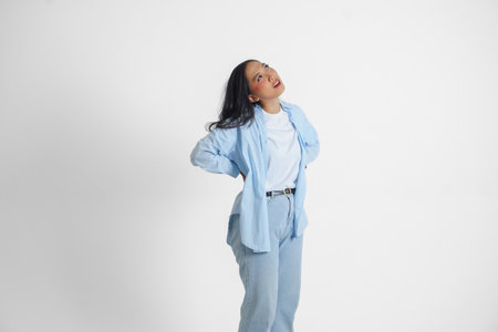 Tired Asian woman wearing a blue shirt suffering from pain, muscle spasm isolated white background.の写真素材