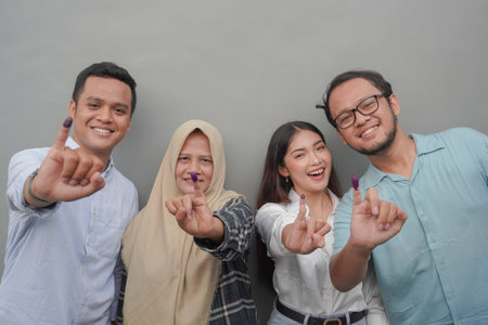 Portrait of excited Indonesian family showing the little finger dipped in purple ink after voting...