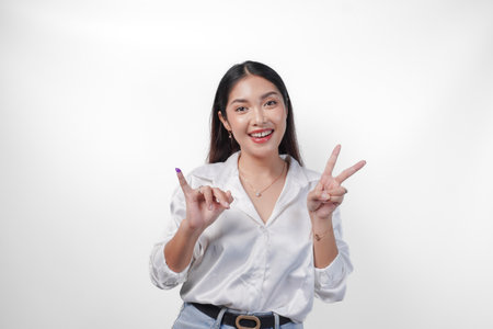 Excited Asian young woman showing little finger dipped in purple ink after voting for Pemilu or Indonesia election and pointing with fingers number one two three, standing on isolated white backgroundの写真素材