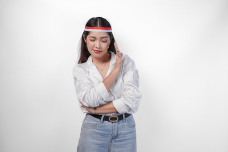 Young Asian woman wearing casual outfit and flag headband showing palm as a refusal and rejection sign, saying no, asking to stop, standing over isolated white backgroundの写真素材