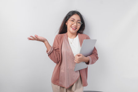 Smiling young Asian business woman holding a laptop with a happy relief expression, isolated by white background.の写真素材