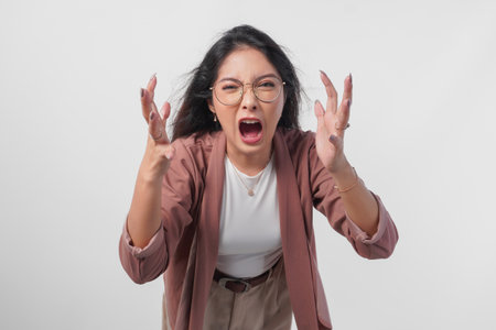 Irritated Asian woman in glasses expressing annoyed, mad, frustrated feelings isolated over white background.の写真素材