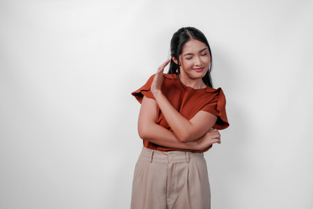 Attractive young Asian woman wearing brown shirt with hand gesture pose rejection or prohibition...